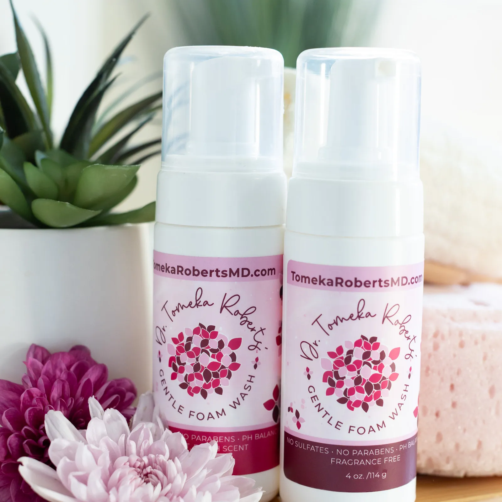 Both Gentle Foam Wash scents on a bamboo tray with a succulent and a bath sponge