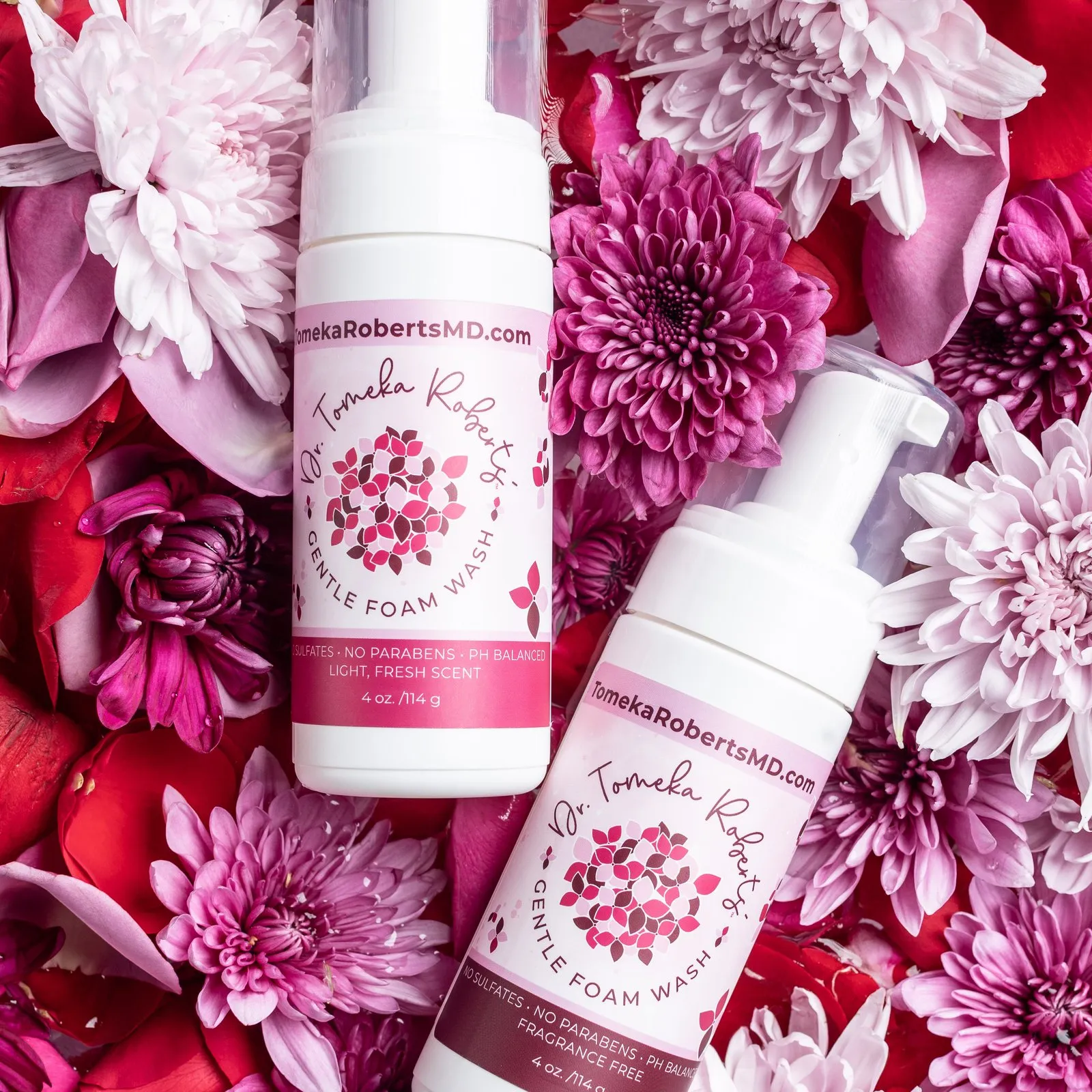 Both Gentle Foam Wash scents resting on a bed of pink and crimson blooms