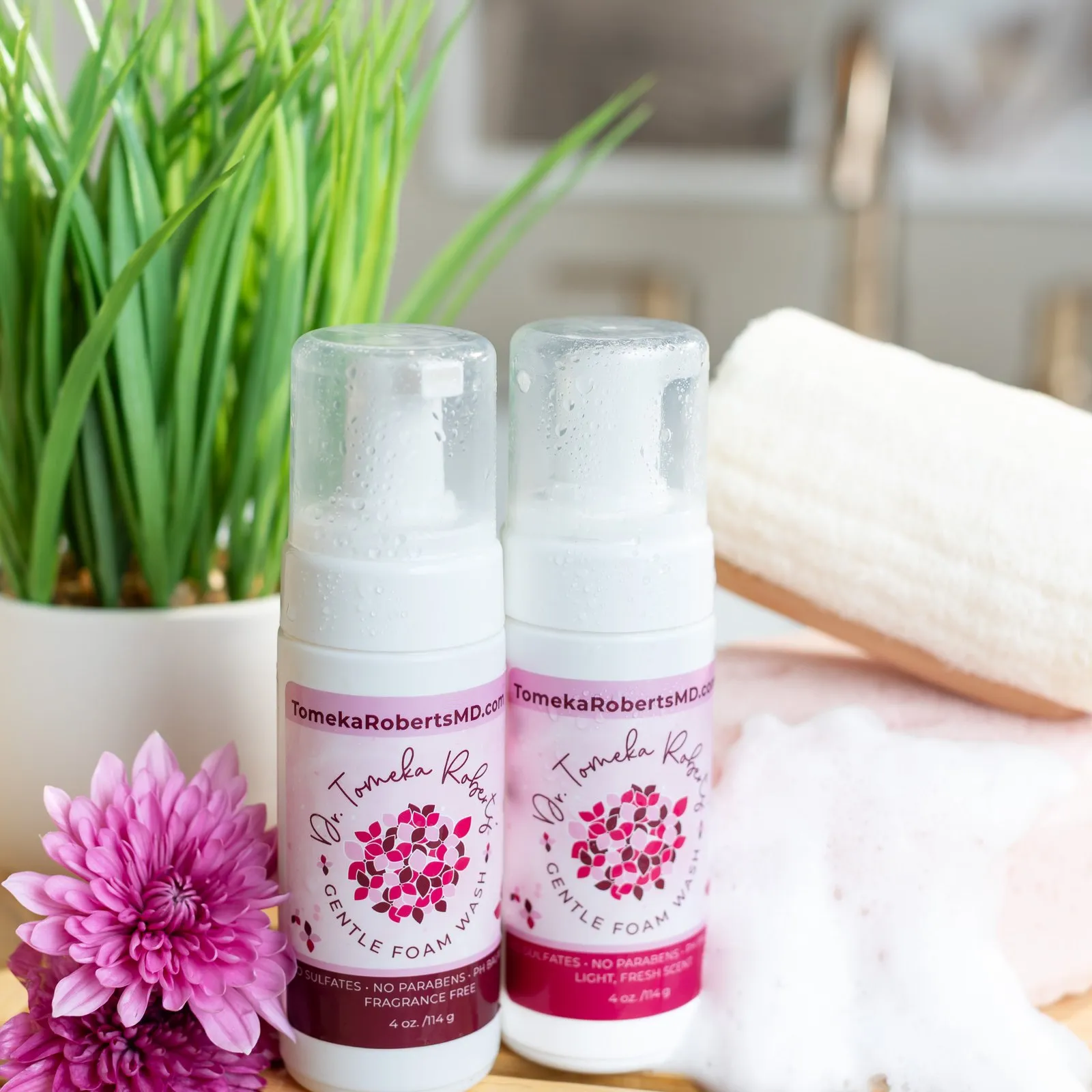 Both Gentle Foam Wash scents styled with foam, a loofah and fresh chrysanthemums